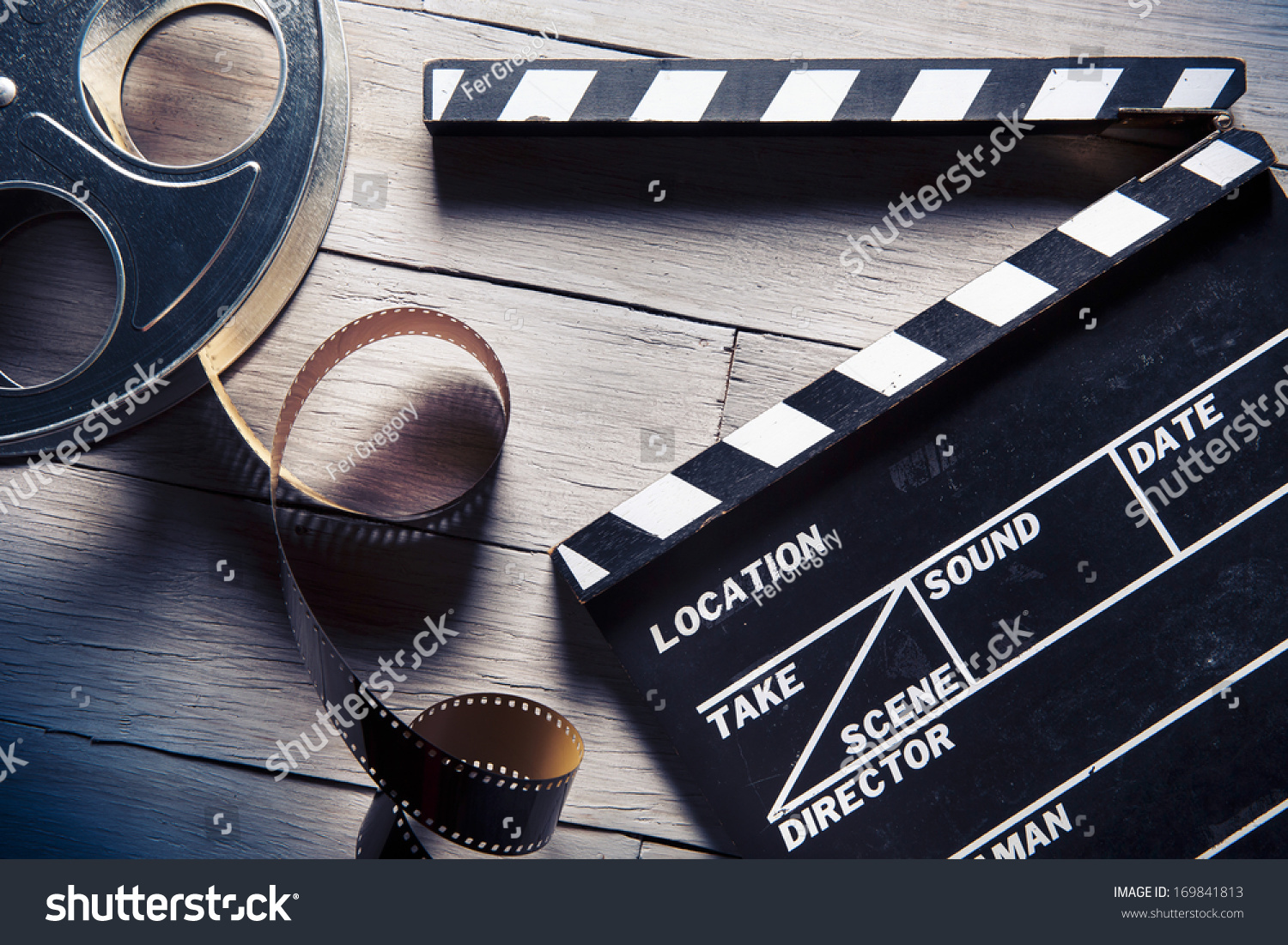 Stock photo movie clapper and film reel on a wooden background 169841813